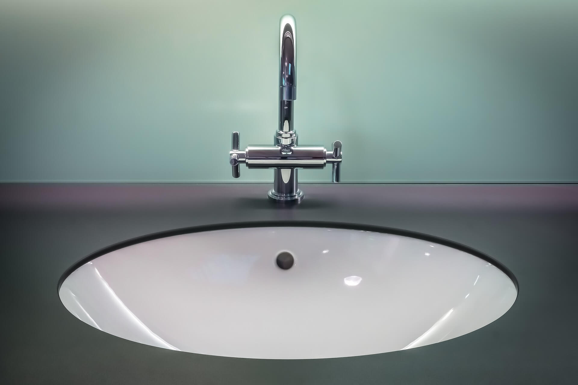 Silver faucet with blue green background. Tips for summer plumbing maintenance